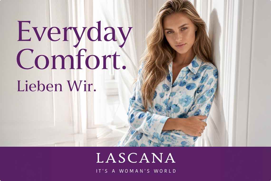 Everyday Comfort. Lieben wir. Frau in gemustertem Schlafanzug lehnt an Wand, LASCANA Logo unten