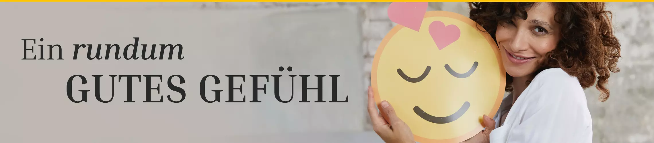 Ein rundum gutes Gefühl: Eine Person hält ein lächelndes Emoji mit Herzchen in den Händen, umgeben von einer hellen Wand.